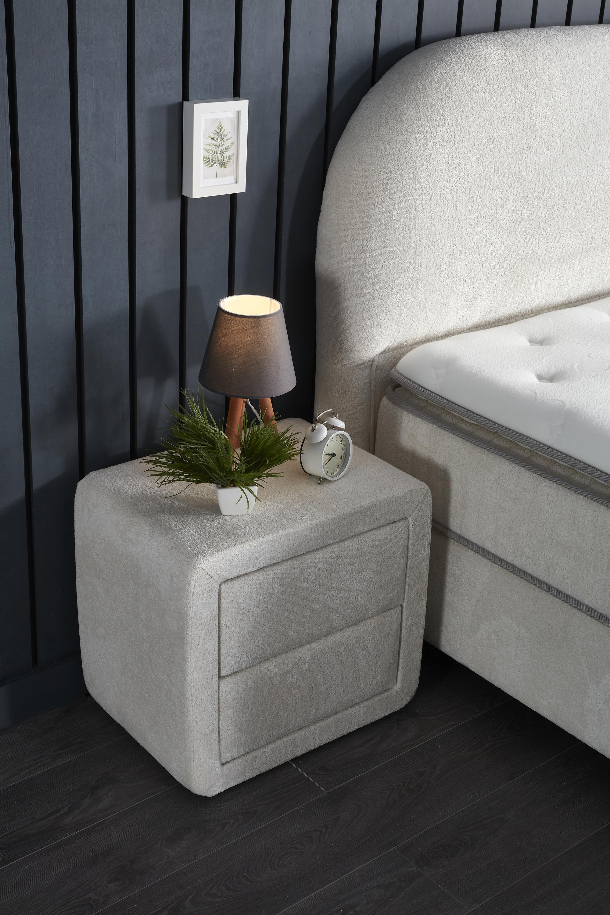 Boxspringbett 'BohemBedd' mit Matratze und Stauraum, auf einem Nachttisch mit Lampe und Uhr, repräsentiert SkyHome24.de's günstige, hochwertige Schlaflösungen.