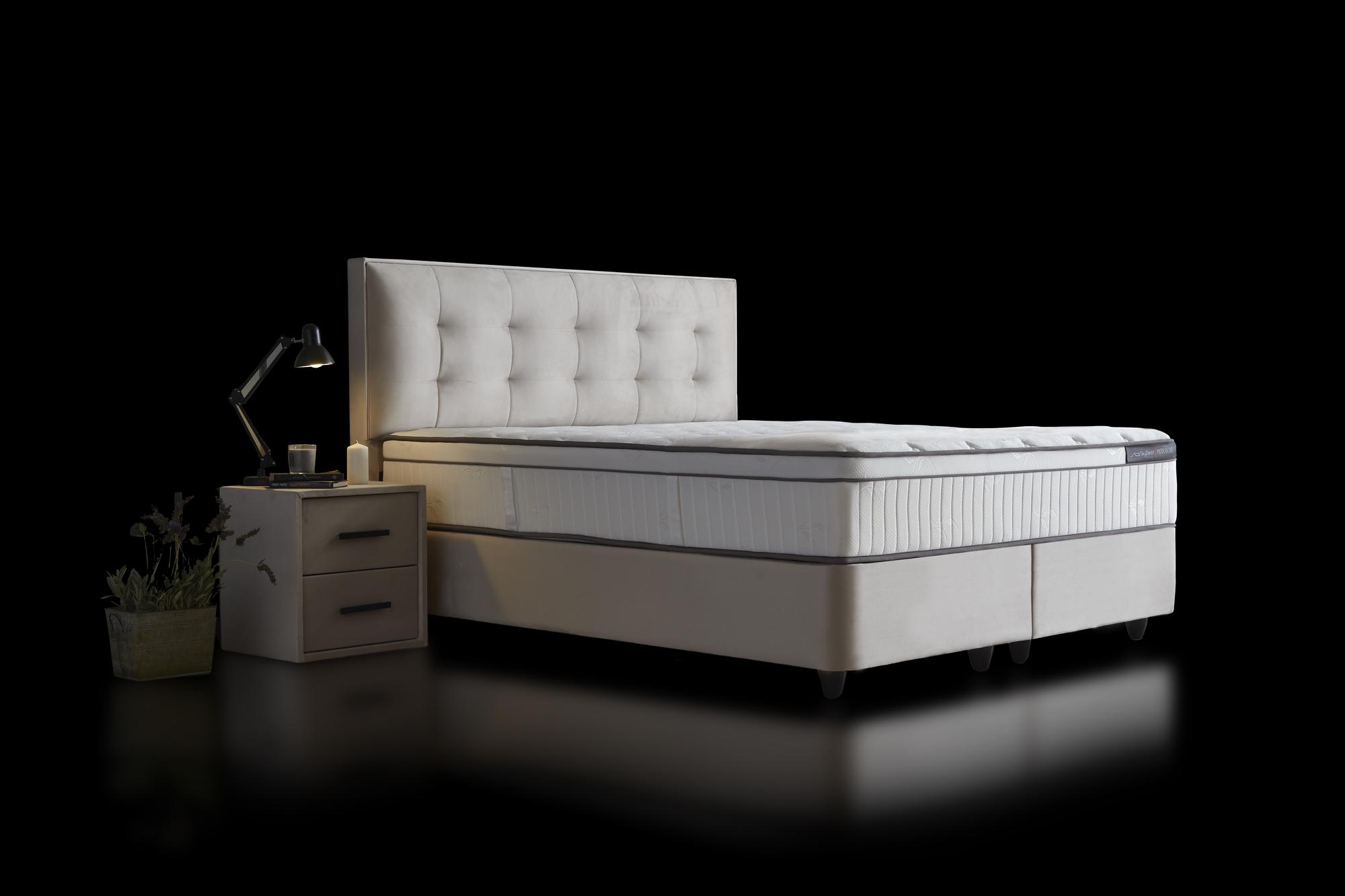 Boxspringbett 'ModeBedd' SkyBedd in Beige/Creme mit Matratze und integriertem Stauraum, ergonomisches Design mit Coil Pro Balance-Technologie, Nahaufnahme von Kopfteil und Nachttisch.