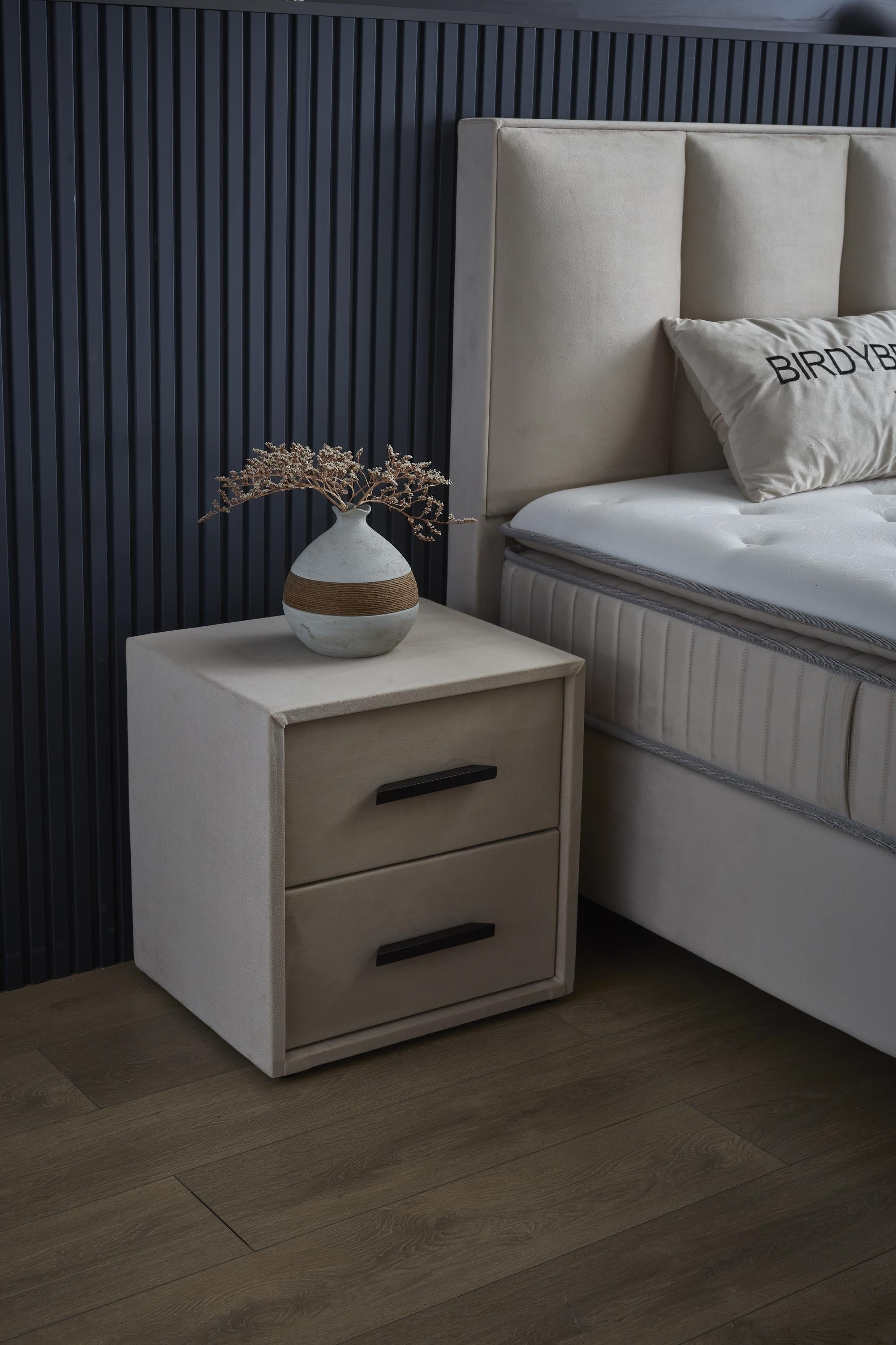 Boxspringbett 'BirdyBedd' SkyBedd mit Matratze und integriertem Stauraum, neben einem weißen Nachttisch mit Schale, dargestellt in einem modernen Schlafzimmer.