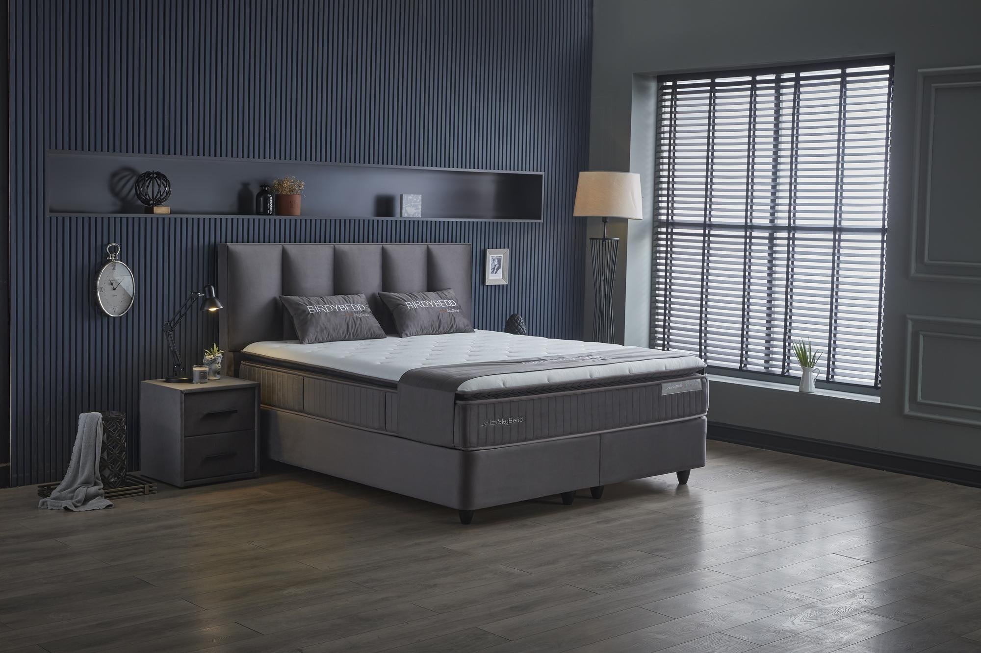 Boxspringbett 'BirdyBedd' SkyBedd mit Matratze und integriertem Stauraum, präsentiert im stilvollen Schlafzimmer mit dekorativen Kissen und Pflanzenakzent.