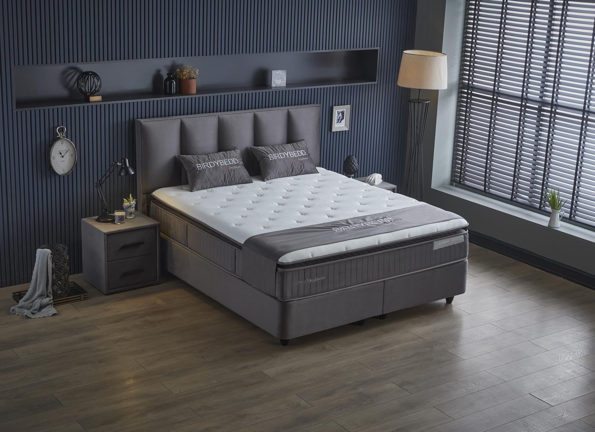 Boxspringbett 'BirdyBedd' SkyBedd mit Matratze und integriertem Stauraum, präsentiert im stilvollen Schlafzimmer, betont durch eine Pflanze in weißem Krug.