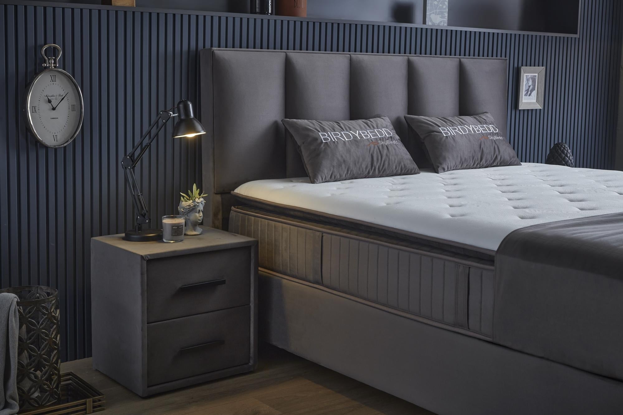 Boxspringbett 'BirdyBedd' SkyBedd in Grau/Anthrazit mit integrierter Matratze und Stauraum, präsentiert in einem stilvollen Schlafzimmerumfeld mit dekorativen Accessoires.