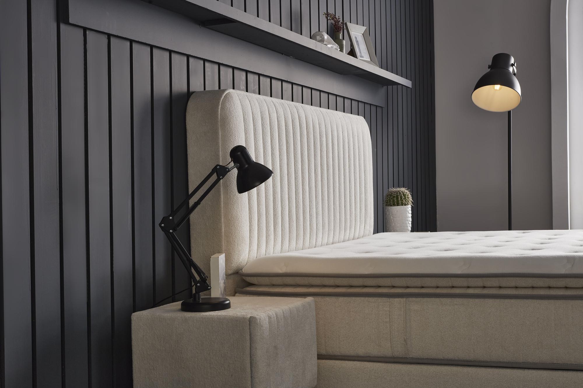 Boxspringbett 'BridaBedd' mit integrierter Matratze und Stauraum, neben einer Lampe platziert. Populäres SkyHome24.de Produkt für günstigen, erholsamen Schlaf.