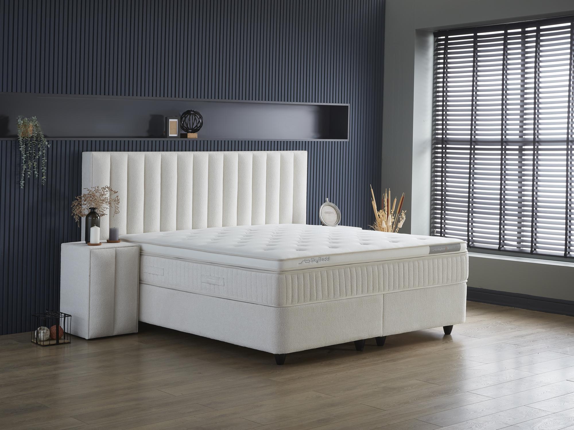 Boxspringbett 'WoollyBedd' mit Matratze, Nahaufnahme von Fenster und Bett, günstiges Angebot bei SkyHome24.de, geeignet für Saugroboter mit integriertem Stauraum.