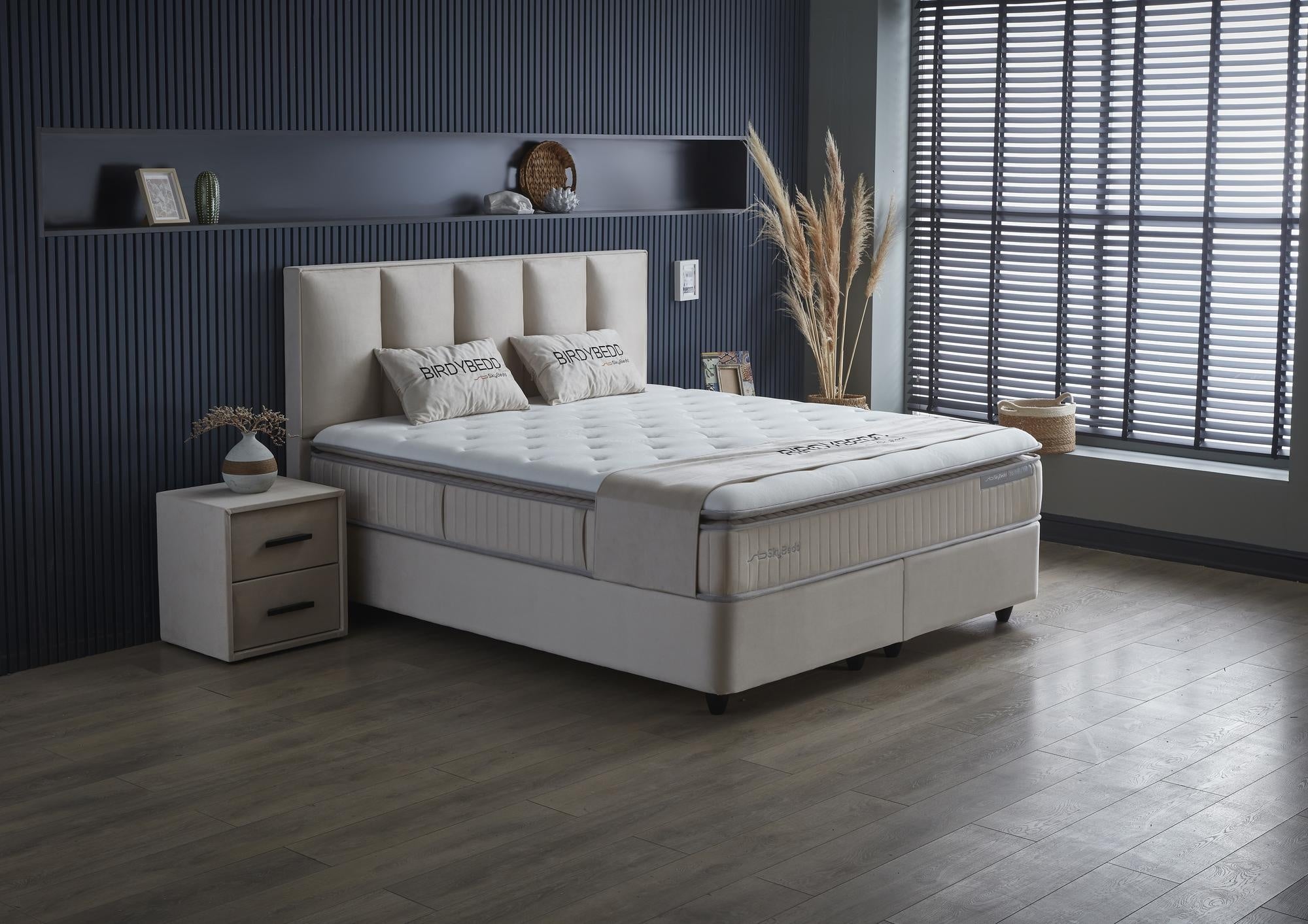 Boxspringbett 'BirdyBedd' SkyBedd in Beige mit orthopädischer Matratze und Stauraum, präsentiert auf einem Bett in einem stilvoll eingerichteten Raum.